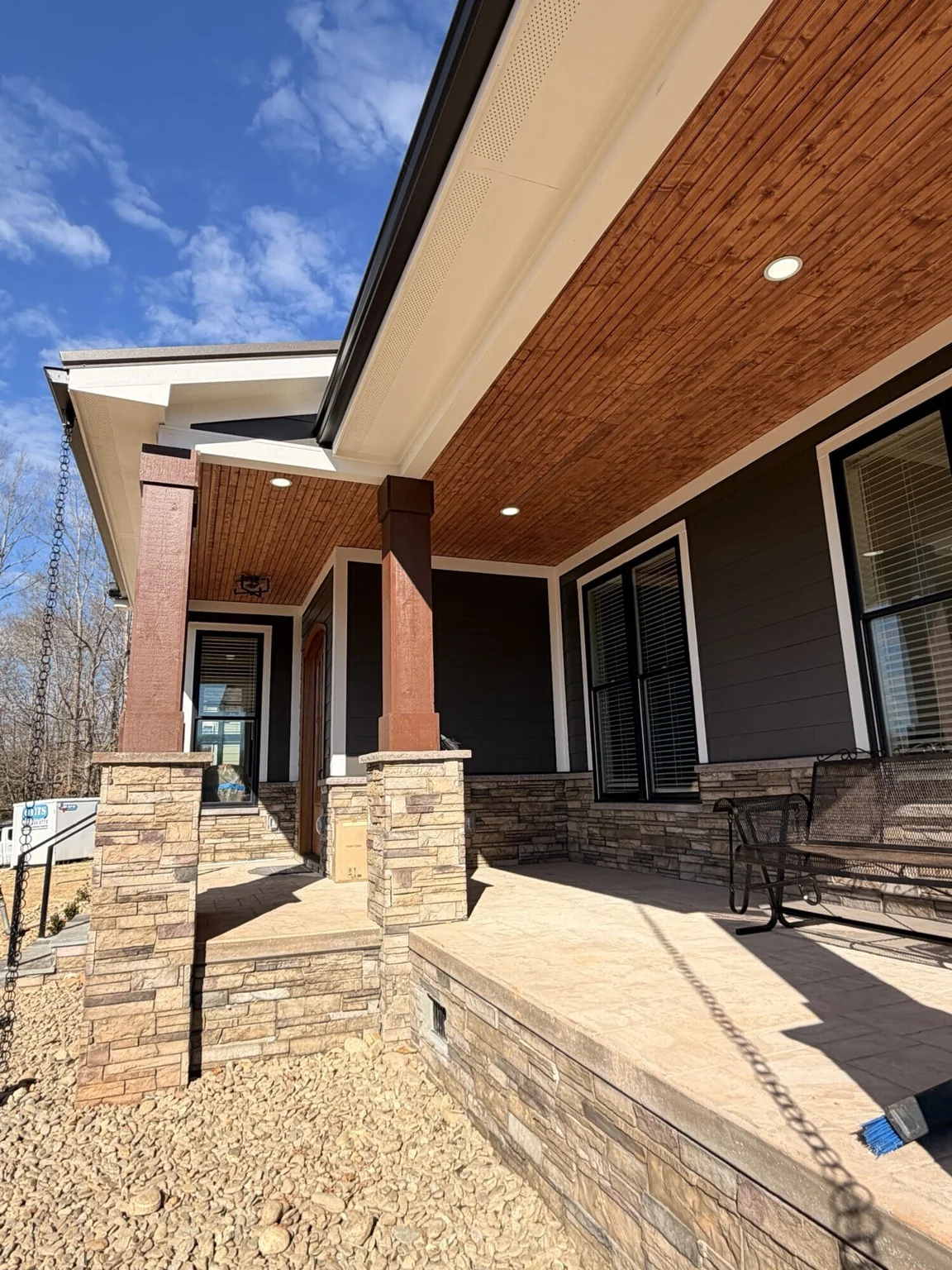 Covered porch with a wood ceiling and stone columns