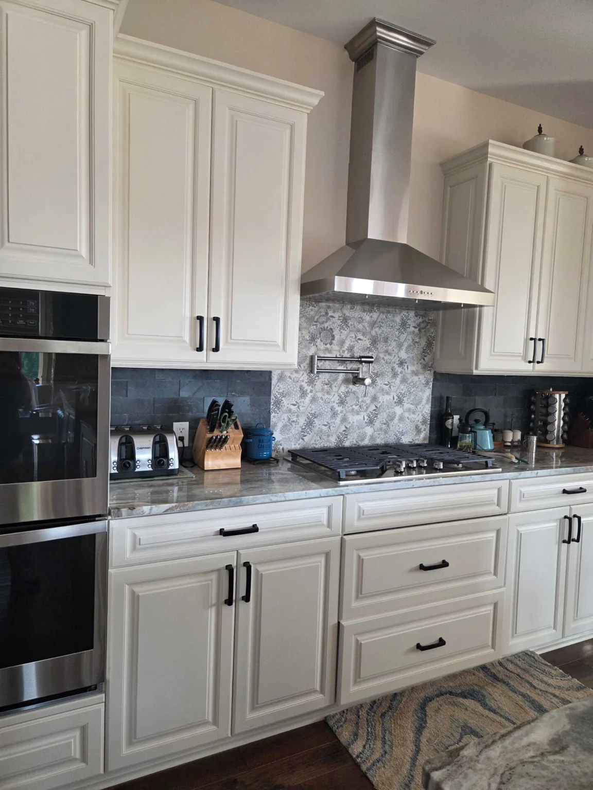 Kitchen cabinetry, range hood, and stone counters at the Marietta residence